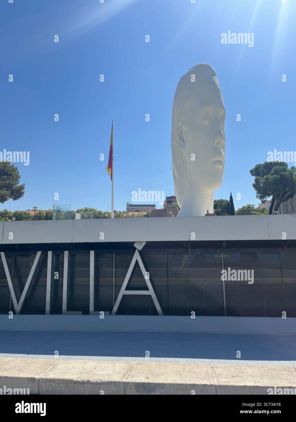 Julia-Skulptur auf der Plaza de Colón in Madrid, Spanien, mit der spanischen Nationalflagge im Hintergrund an einem hellen, sonnigen Sommertag. Stockfoto
