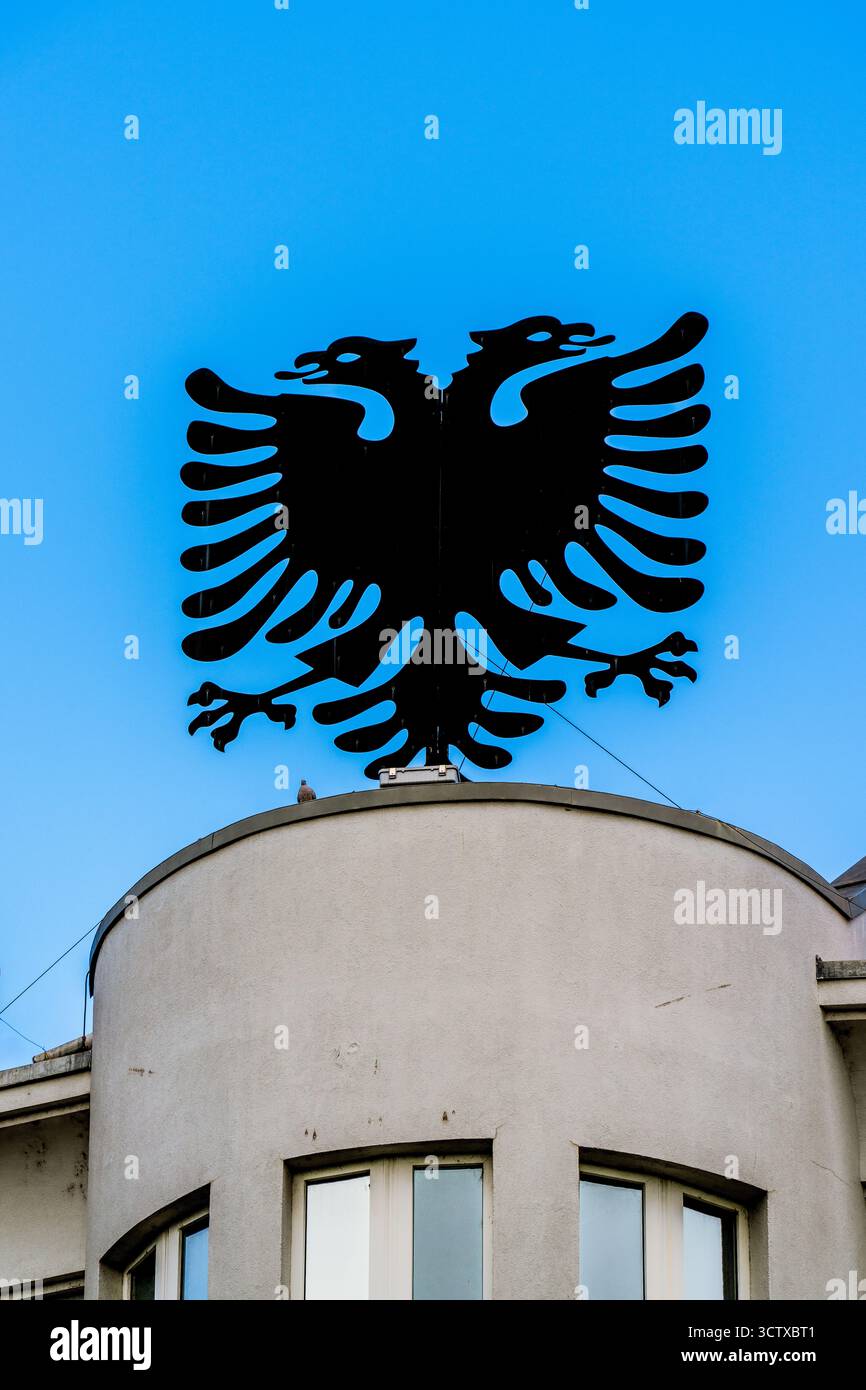 Doppelköpfiges Adler-Emblem auf der Gebäudefassade, das das nationale Symbol Albaniens gegen den klaren blauen Himmel darstellt Stockfoto