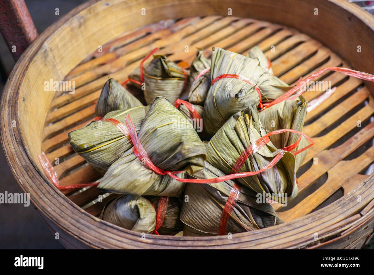 Klebrige Reisknödel (Bajang), in Blätter gewickelt, in einem Bambusdampfer ausgestellt. Klassische thailändische/chinesische Street Food-Tradition. Stockfoto