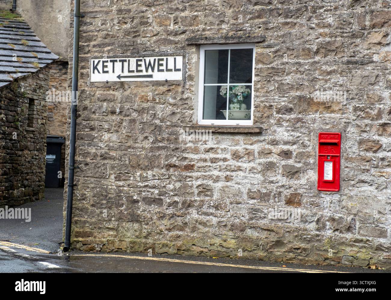 Ein Straßenschild an einer Hauswand in Gayle, das die Richtung nach Kettlewell, North Yorkshire, England zeigt Stockfoto
