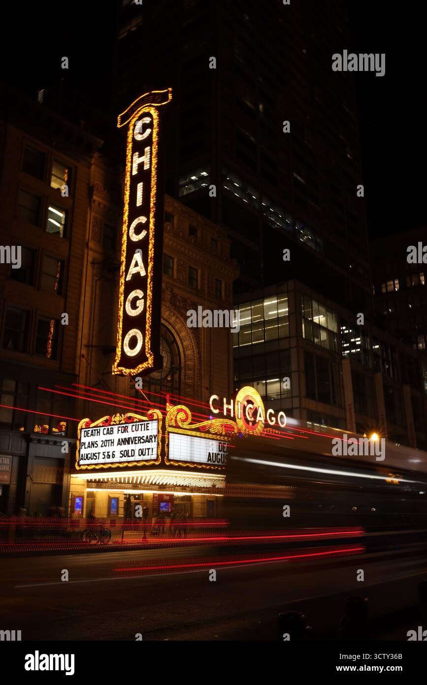 Das legendäre Chicago Theatre-Schild leuchtet nachts. Lange Belichtungsspuren vom Verkehr geben der lebhaften Stadtstraße Bewegung. Stockfoto
