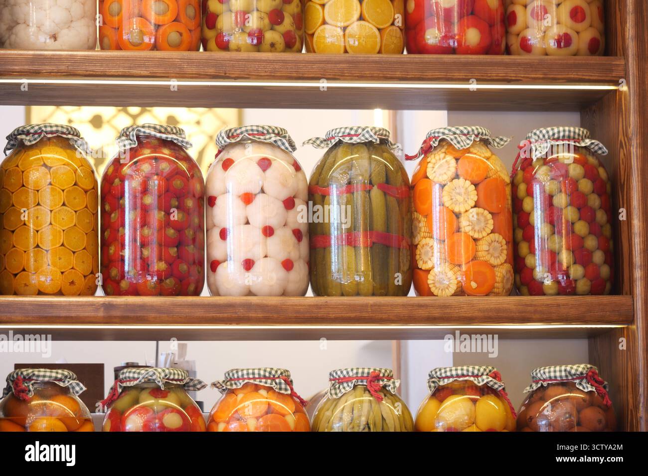 Gläser mit bunten Früchten und Gemüse in Regalen Stockfoto