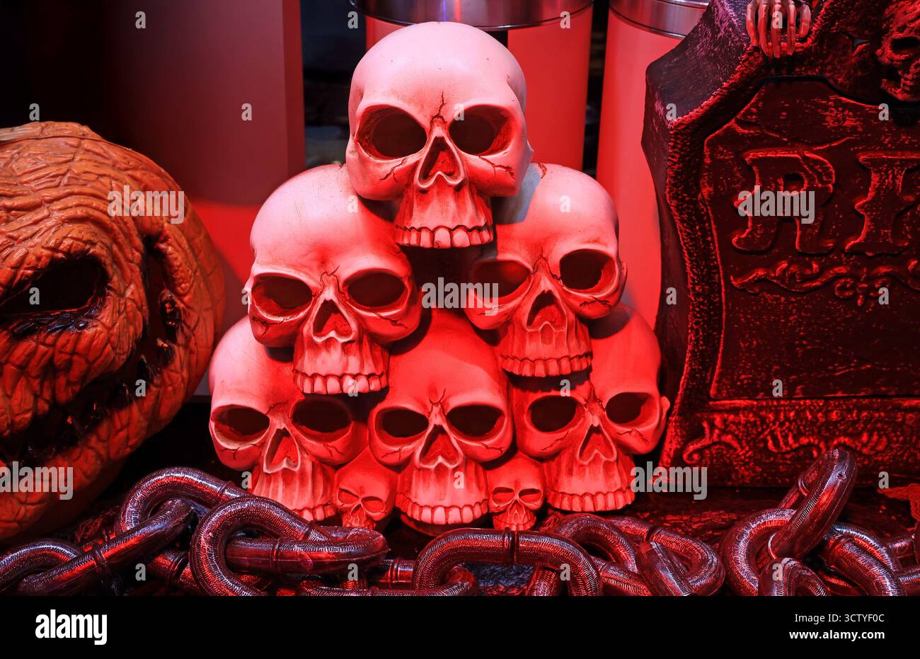 Gruselige Halloween-Dekoration mit einem Haufen beleuchteter Schädel und Grabstein Stockfoto