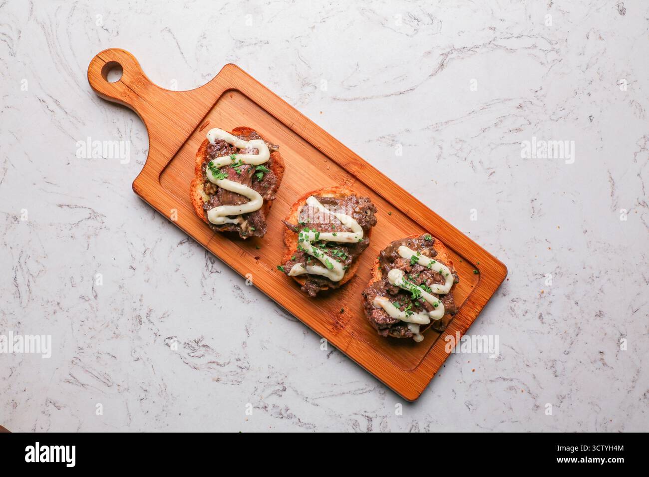 Geröstetes Rindfleisch-Crostini-Baguette, Steakscheiben, karamelisierte Zwiebeln und Pilze, Blaukäse Stockfoto