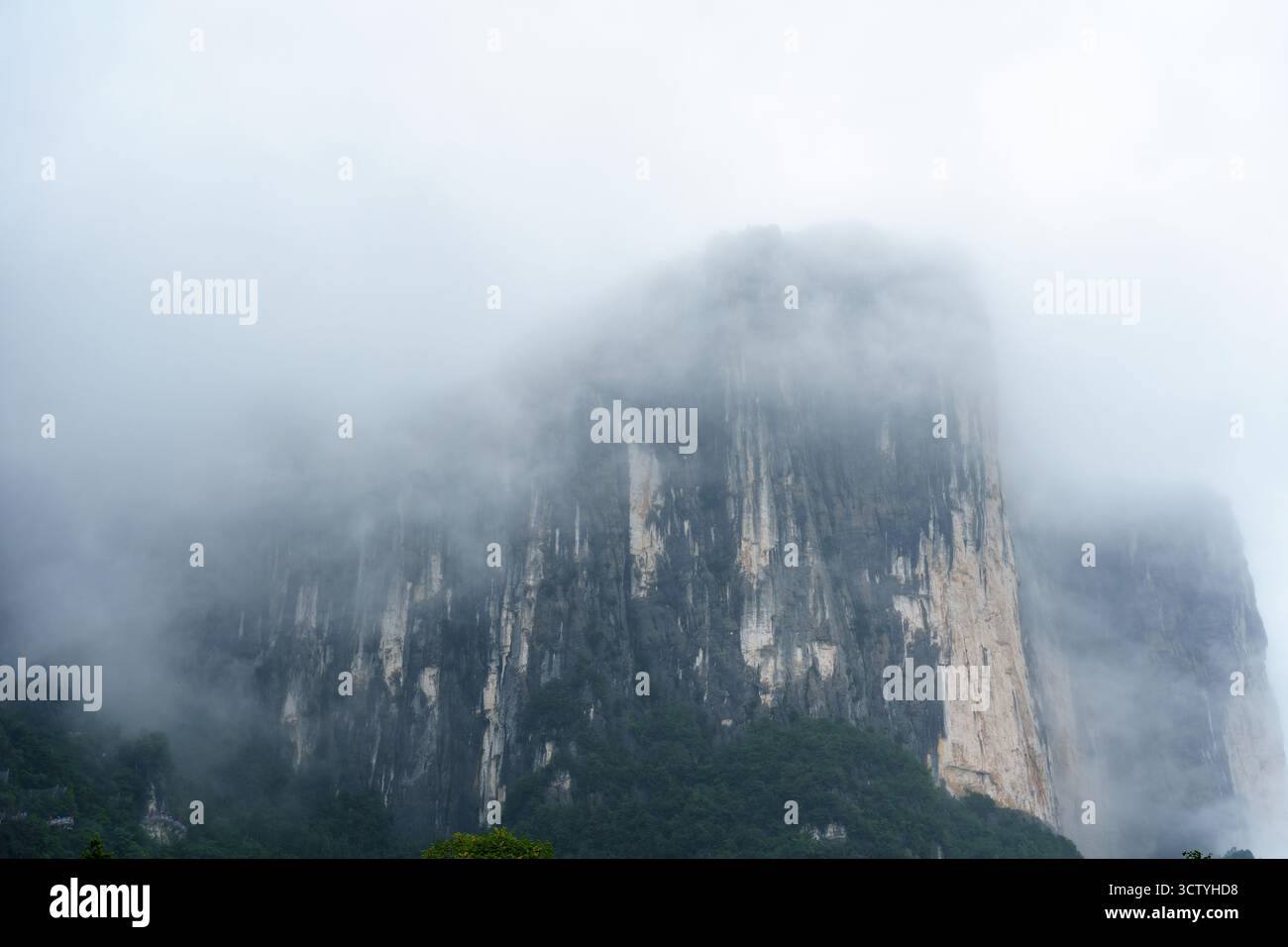 Die nebligen Berge erheben sich majestätisch in Yichang City, China, mit ihren steilen Klippen, die in atmosphärischen Nebel gehüllt sind, und schaffen eine ruhige und ehrfurchtvolle Natur Stockfoto