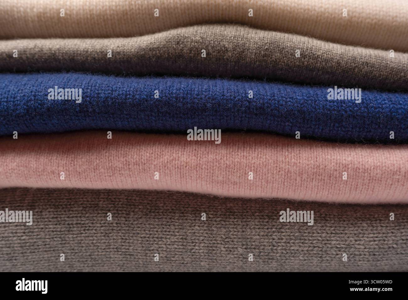 Eine Gruppe warmer Pullover auf weißem Hintergrund. Stapel gefalteter Pullover auf weißem Hintergrund. Stockfoto