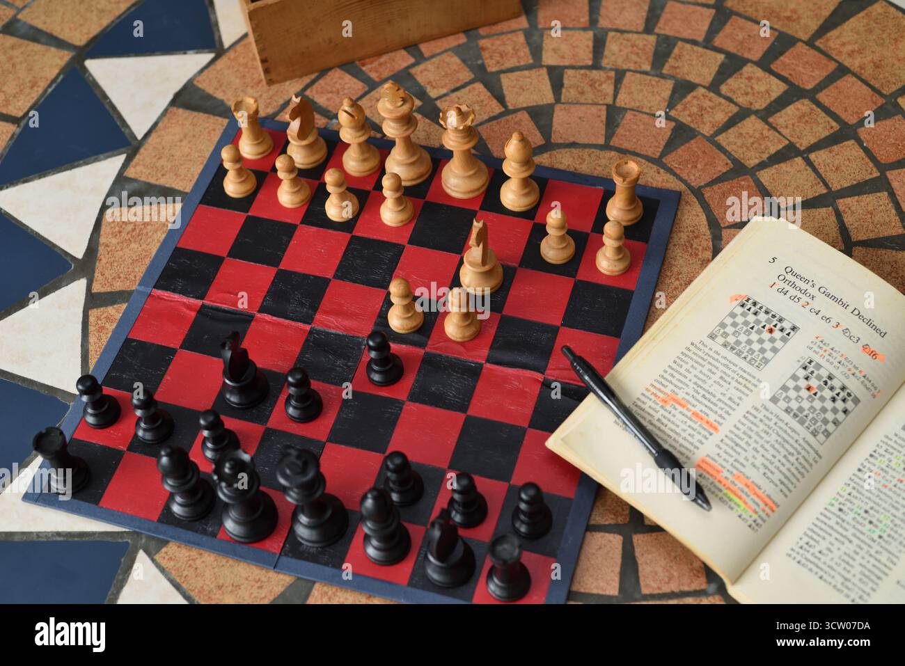Eröffnungszüge in The Queens Gambit lehnten ab, lernten Schacheröffnungen aus einem Schachbuch und spielten mit klassischen Staunton Schachmännern. Stockfoto