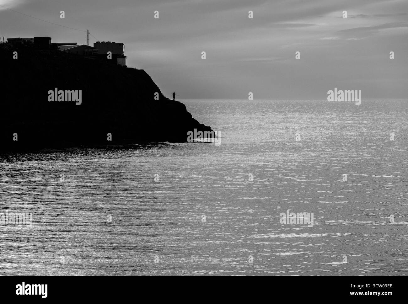 Einsamer Fischer in der Dämmerung, wenn der Tag zu Ende geht New Quay Wales Großbritannien. Juli 2025 Stockfoto