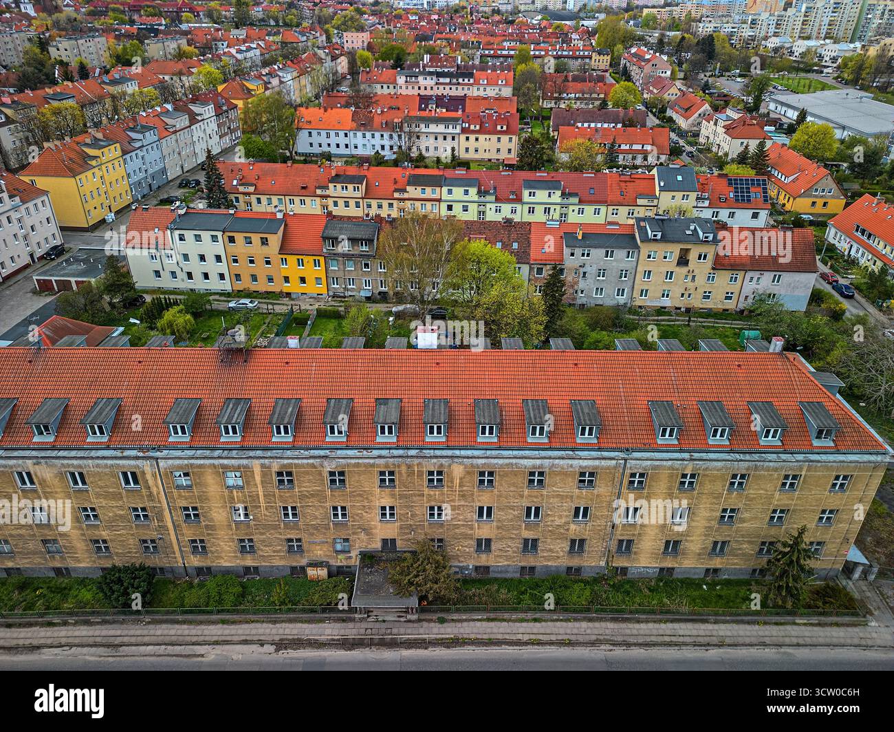 Historisches, gelbes Backsteingebäude mit rotem Ziegeldach, umgeben von farbenfroher Wohnarchitektur in Danzig mit Blick auf die städtische Landschaft Stockfoto