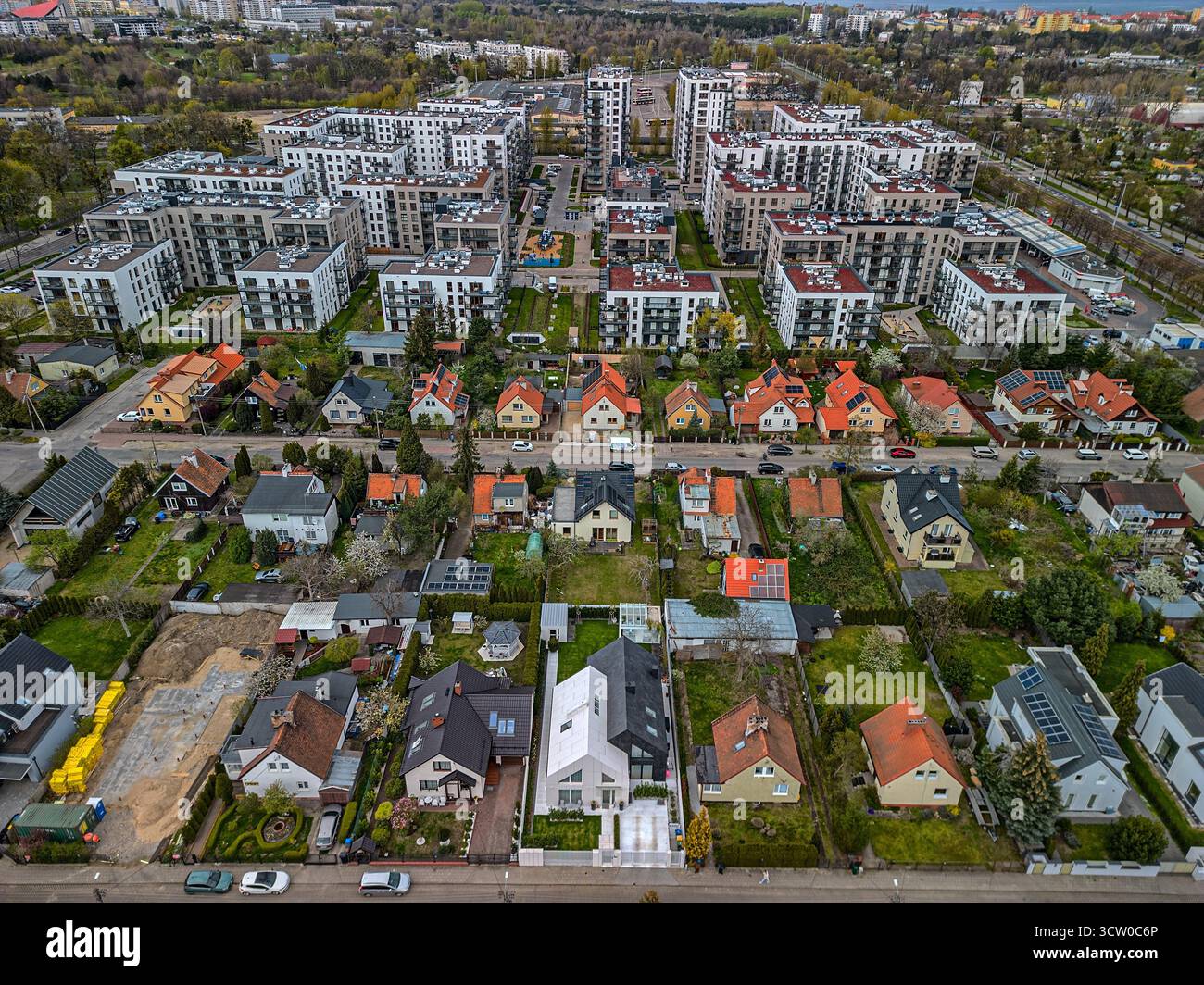 Gemischte Wohnsiedlung aus der Vogelperspektive im Kontrast zu traditionellen Häusern und modernen weißen Apartmentkomplexen in polnischer Stadtplanungslandschaft Stockfoto