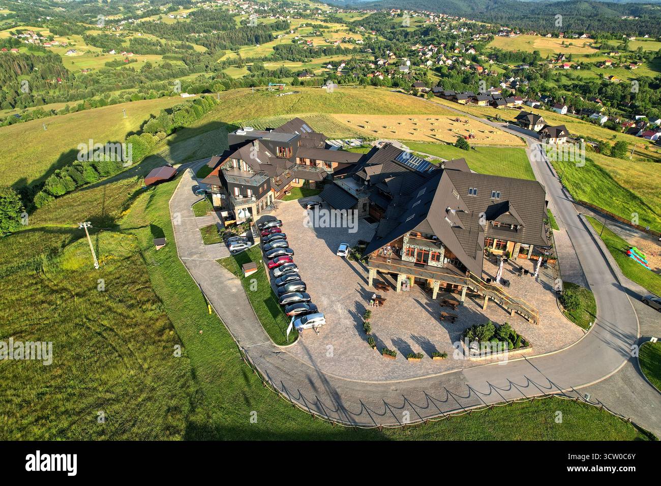 Drohnenblick auf das Hotel Zloty Gron Istebna zur goldenen Stunde, Landschaftsorientierung, Weitwinkelkomposition, lebendige natürliche Beleuchtung, Panorama-Resort Stockfoto