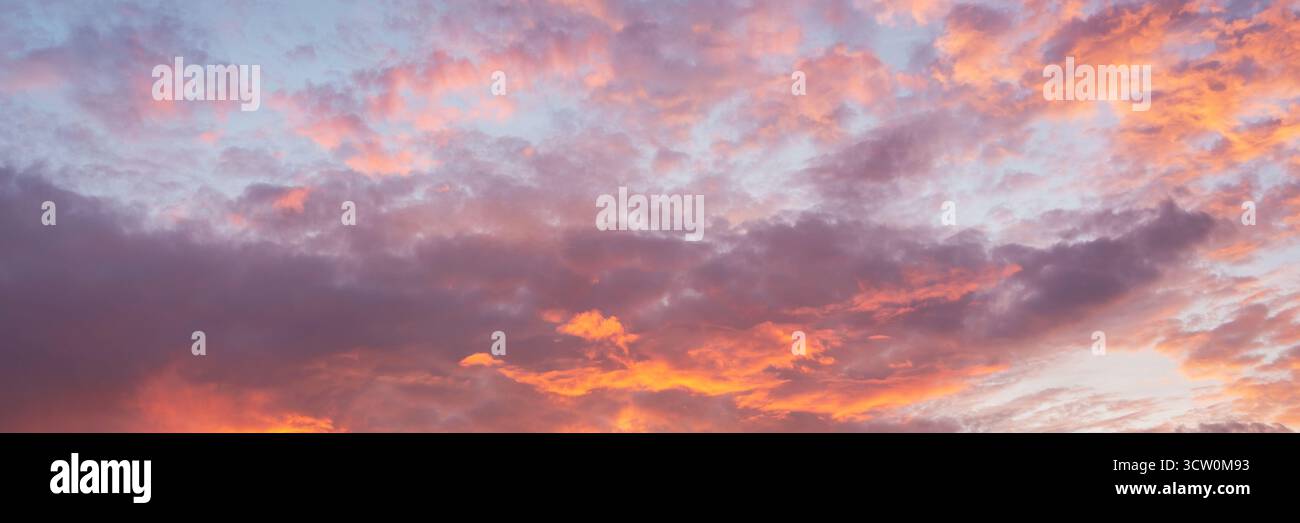Wunderschöner orangefarbener Himmel bei Sonnenuntergang mit rosa Wolken, Panoramahintergrund der Natur Stockfoto