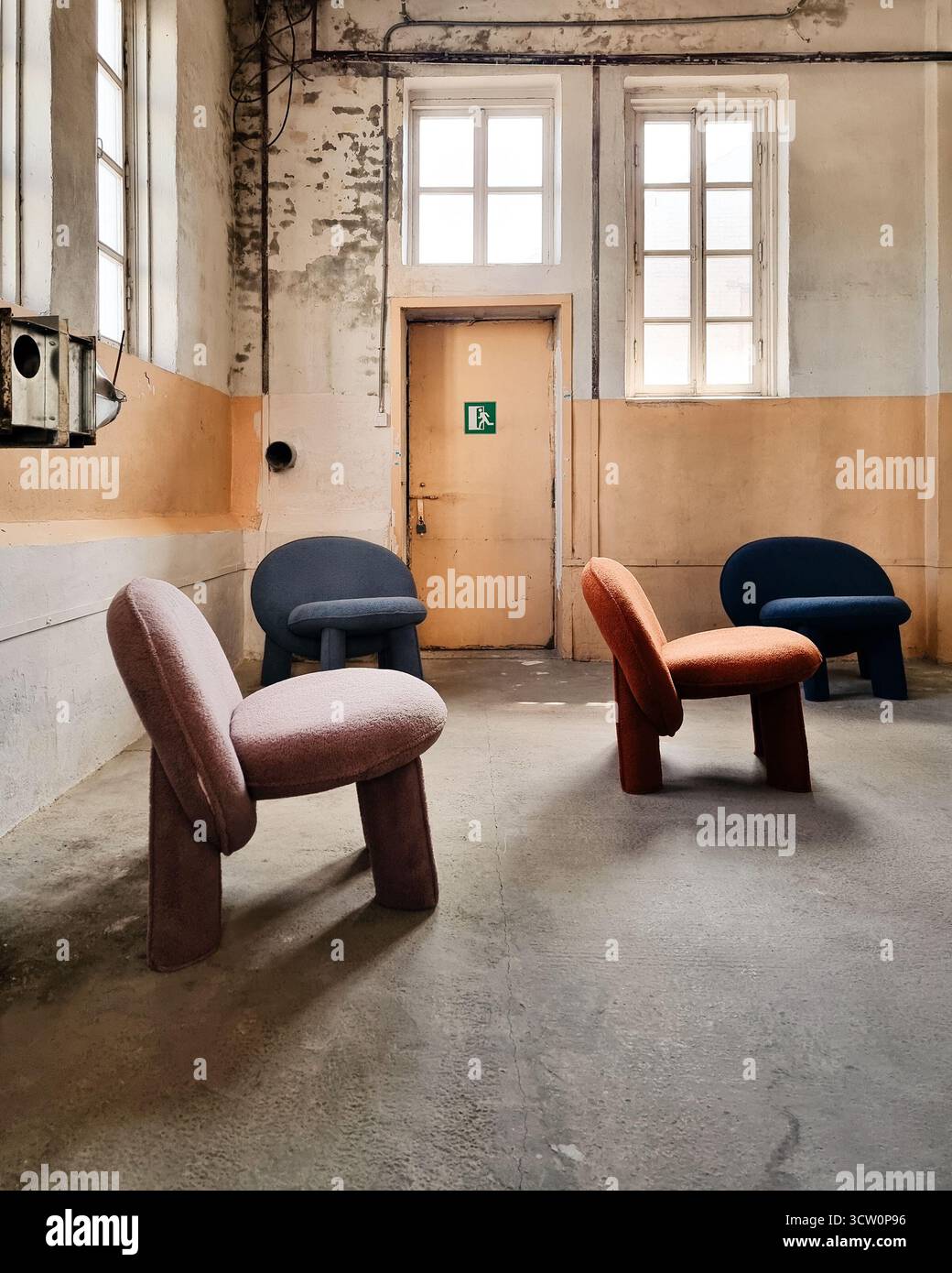 Innenraum des Loft - altes leeres Fabrikzimmer mit fünf zufällig platzierten Plüschstühlen. Stockfoto