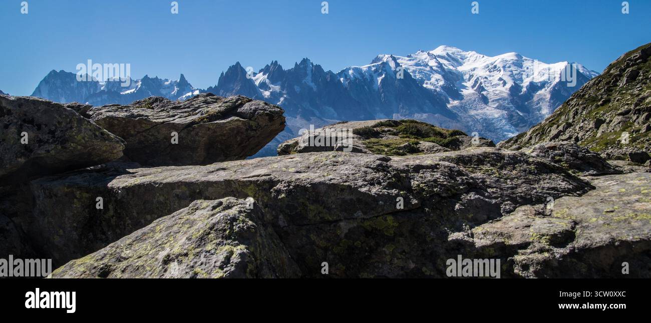 Die majestätische Bergkette bietet scharfe Gipfel und Gletscher, die während Eines sonnigen Tages erfasst werden. Felsen Im Vordergrund Verleihen Der Atemberaubenden Landschaft Sc Tiefe Stockfoto