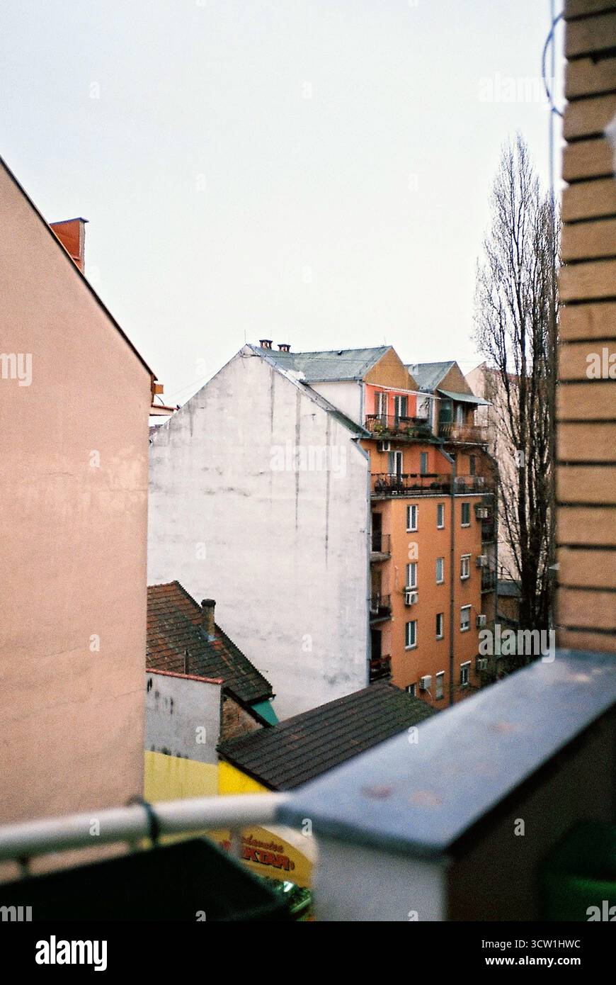 Analoges Foto von einem Balkon eines Gebäudes aus der sozialistischen Ära mit Blick auf ähnliche gelbe Backsteingebäude. Bedeckter Himmel. Dokumentarische Stadtarchitektur Stockfoto