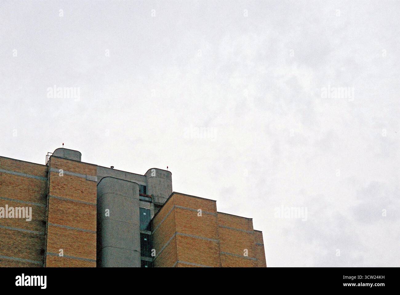 Analoges Foto des sozialistischen Backsteinbaus mit bewölktem Himmel und negativem Raum. Stockfoto