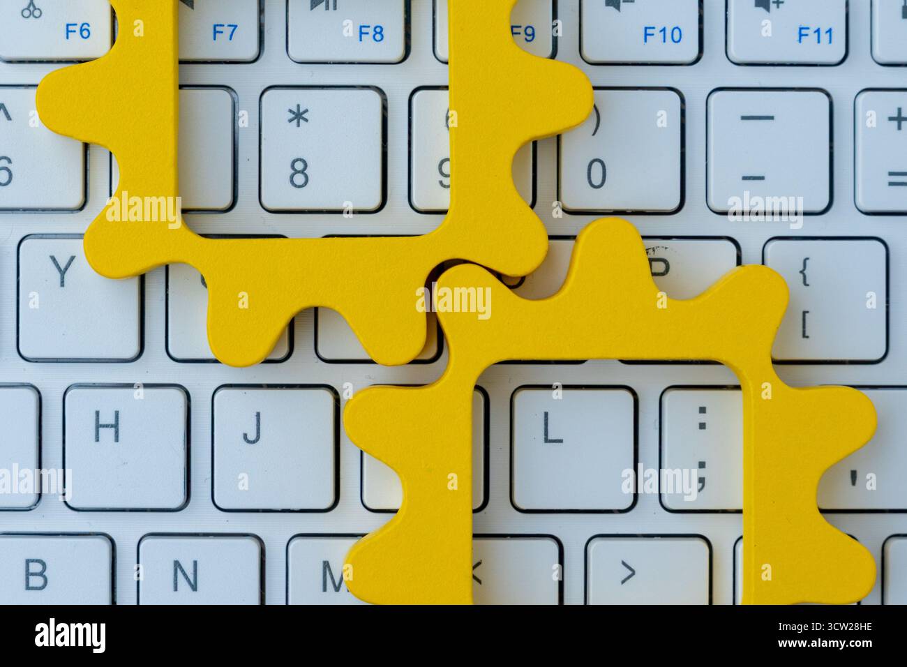 Gelbe Zahnradformen auf einer Computertastatur symbolisieren Automatisierung in Computersystemen, digitale Arbeitsabläufe und technologische Prozessintegration. Stockfoto