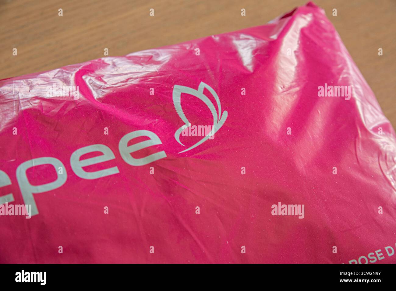 Eine Nahaufnahme einer glänzenden pinkfarbenen Veepee-Verpackungstasche, die das Markenlogo und das Schmetterlingsemblem in einem eleganten und modernen Design unterstreicht. Stockfoto