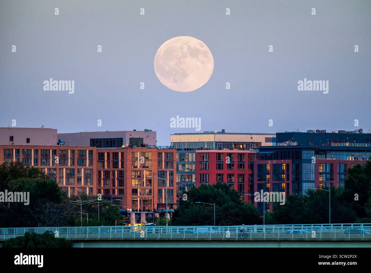 Harvest Moon über der Skyline der Südwestküste Washington DC // WASHINGTON DC — der Harvest Moon im Oktober 2025 erhebt sich am 6. Oktober 2025 über der 14th Street Bridge und der Skyline der Südwestküste. Dieser Vollmond, der der herbstlichen Tagundnachtgleiche am nächsten kommt, wird mit landwirtschaftlichen Ernten in Verbindung gebracht. Die Southwest Waterfront ist ein wiederbelebter Stadtteil am Potomac River mit modernen Gebäuden und der Entwicklung der Wharf. Der 14th Street Bridge Complex, offiziell Arland D. Williams Jr. Memorial Bridge verbindet Washington DC mit Arlington, Virginia. Stockfoto