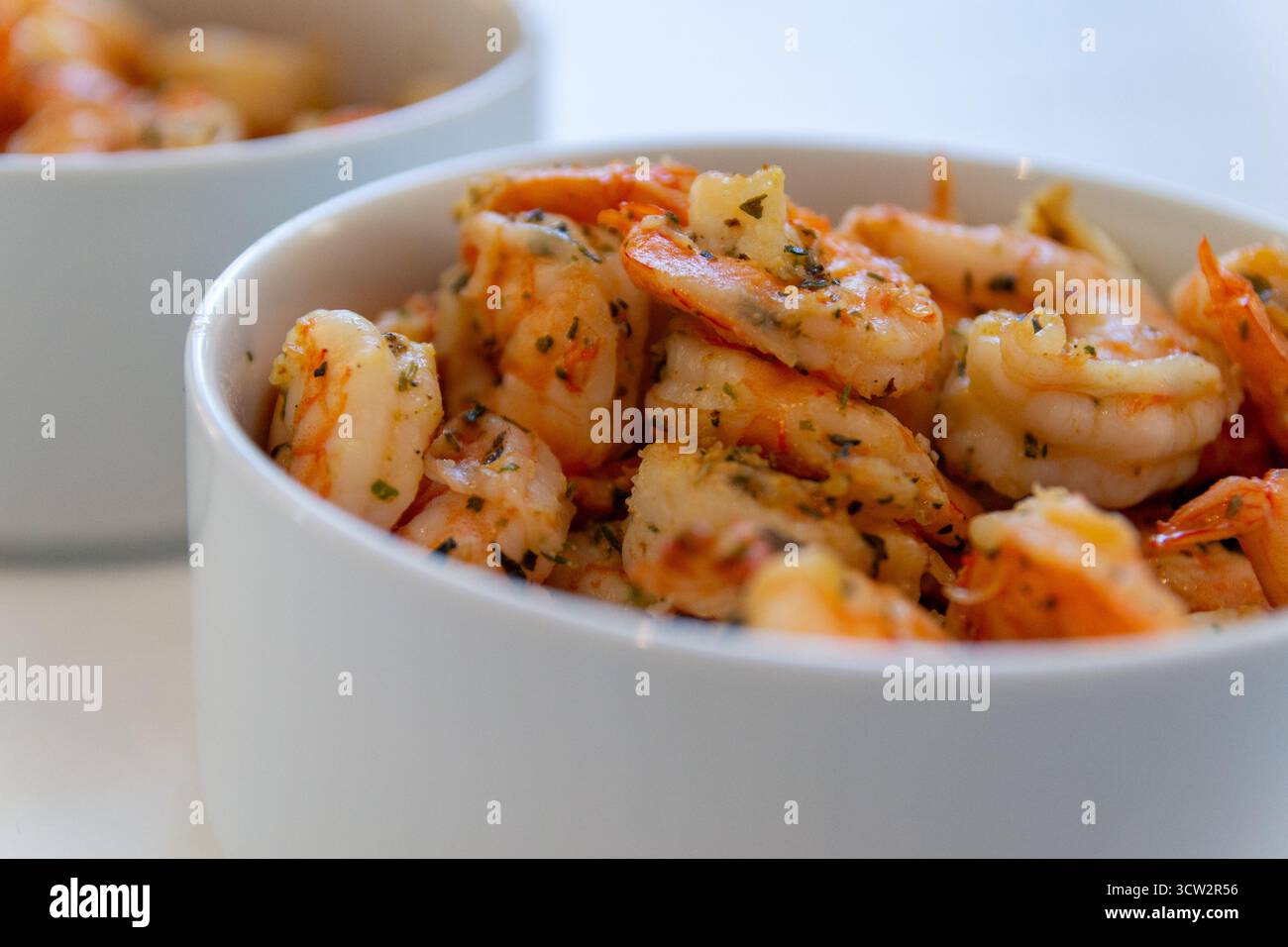 Knoblauchbutter Garnelen in White Bowl – Nahaufnahme gekochter Garnelen mit Kräutern Stockfoto
