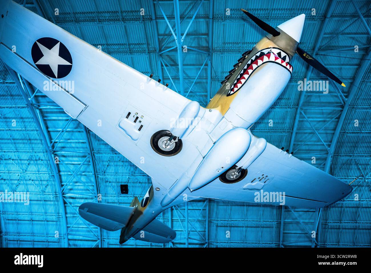 Curtiss P40E Warhawk Smithsonian Air and Space Museum Chantilly VA // CHANTILLY, Virginia — das Curtiss P-40E Warhawk mit seiner berühmten Haifischmaus-Nasenart und den US-Star-Insignien wird im Steven F. Udvar-Hazy Center ausgestellt. Dieses einmotorige, einsitzige Kampfflugzeug war ein erfolgreiches, vielseitiges Flugzeug in der ersten Hälfte des Zweiten Weltkriegs, das ursprünglich als Kittyhawk I nach Kanada geliefert wurde und bei der Royal Canadian Air Force diente. Es wurde 1975 restauriert, um ein Flugzeug der 75th Fighter Squadron, 23rd Fighter Group, 14th Air Force, bei der Smithsonian National Air and Space zu repräsentieren Stockfoto