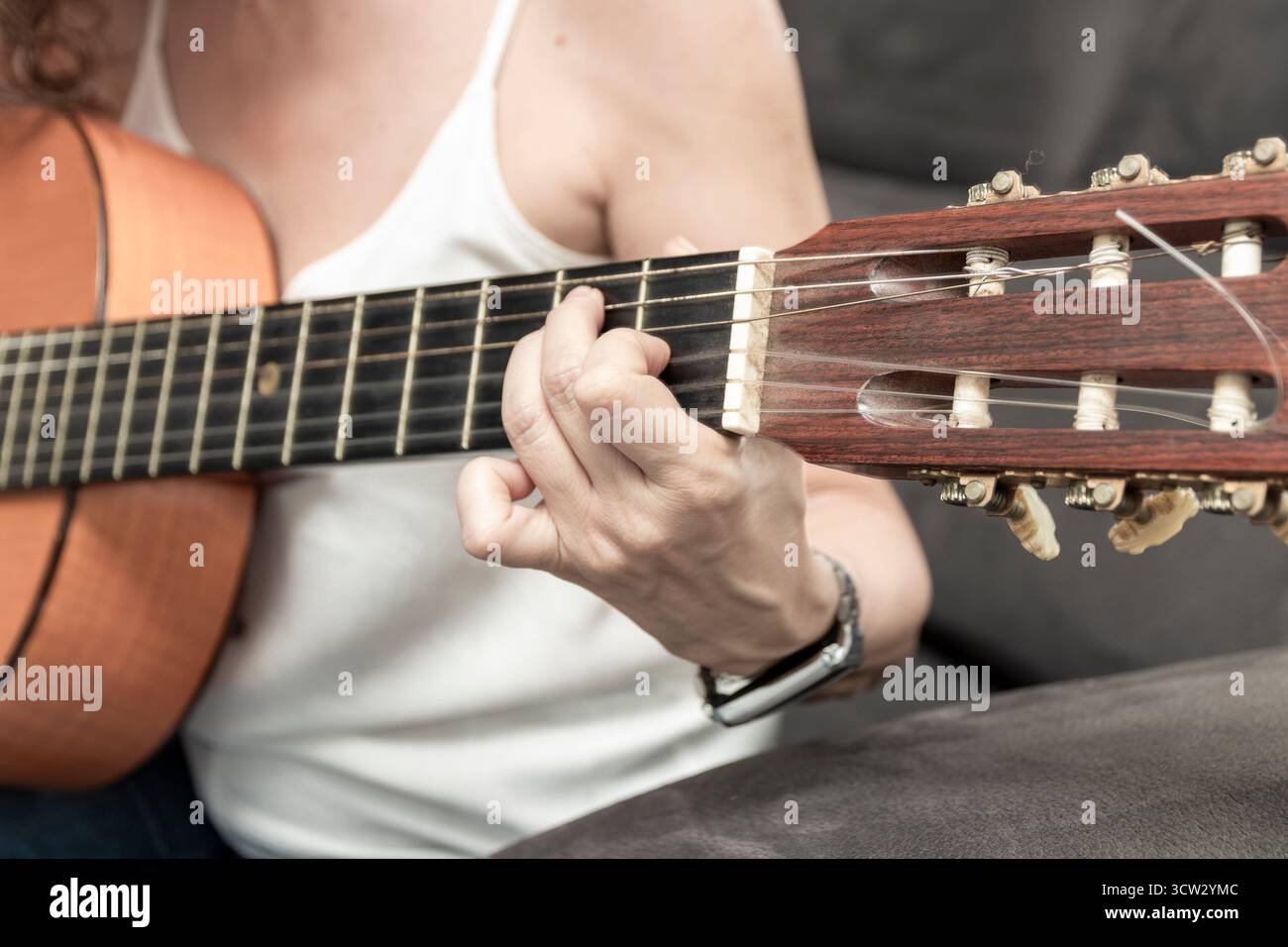 Frauenhände drücken Griffbrettsaiten der klassischen Gitarre und kreieren Musik Stockfoto