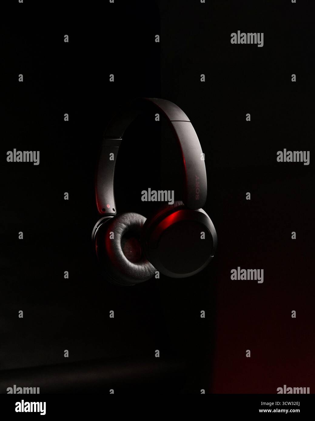 Elegante, mattschwarze Kopfhörer, beleuchtet durch einen dramatischen roten Rand vor einem pechschwarzen Hintergrund Stockfoto