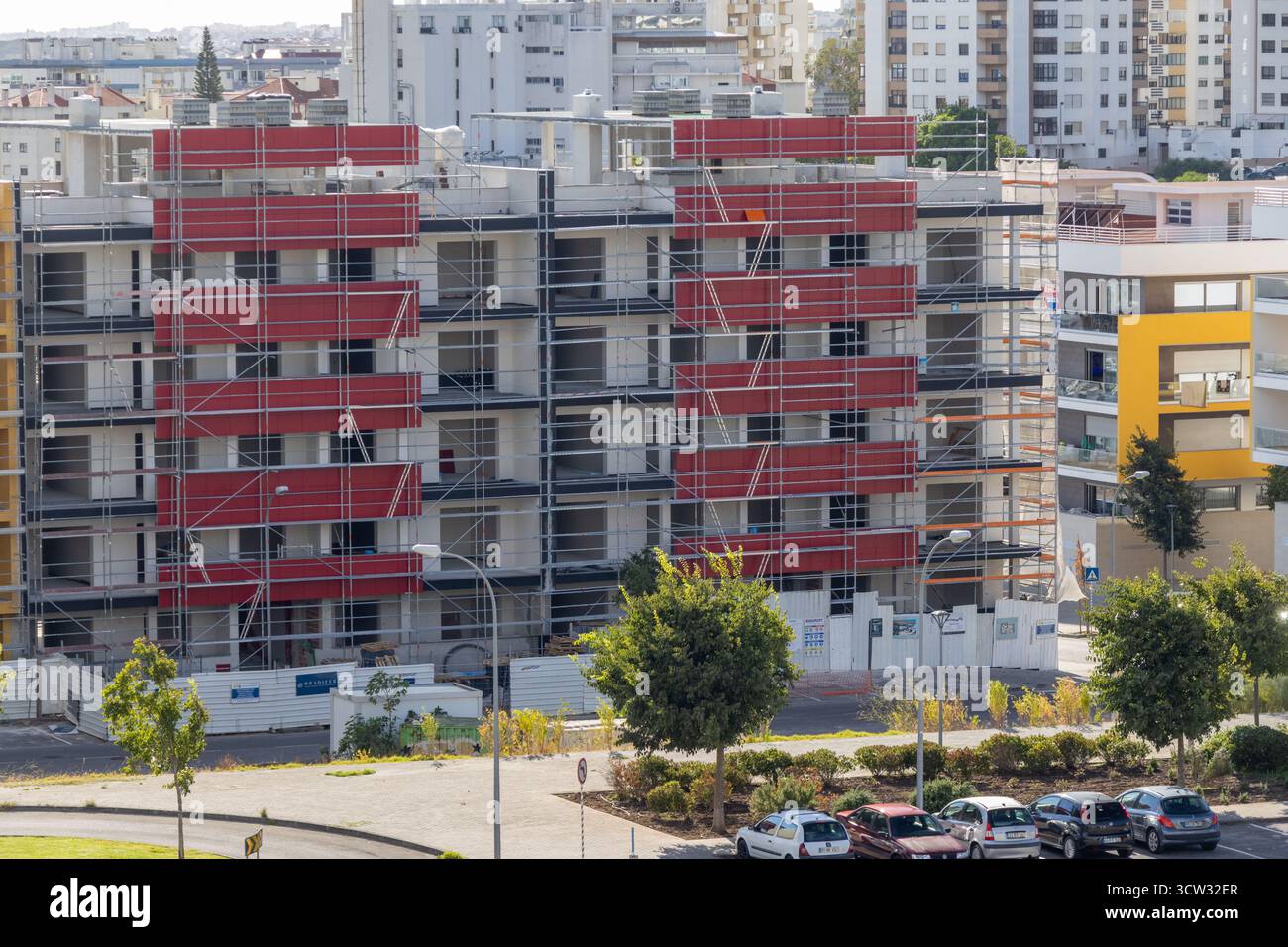Rotes Gerüst, das ein im Bau befindliches Gebäude in einem städtischen Gebiet abdeckt und Wachstum und Entwicklung repräsentiert Stockfoto
