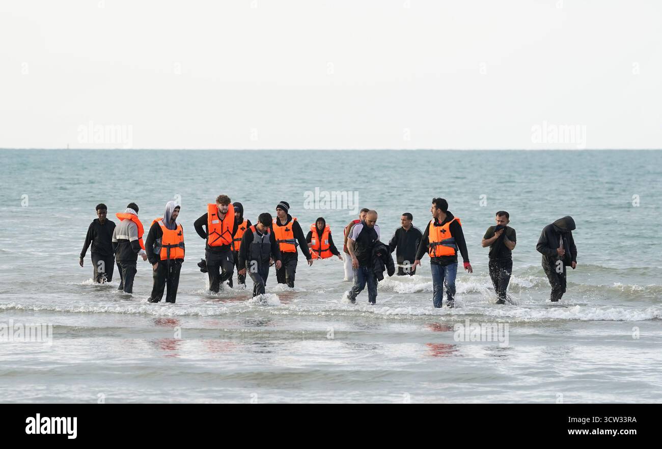 Menschen, die als Migranten gelten, waten durch das Meer, nachdem sie vergeblich versucht hatten, an Bord eines kleinen Bootes in Gravelines, Frankreich, zu gehen. Bilddatum: Donnerstag, 9. Oktober 2025. Stockfoto