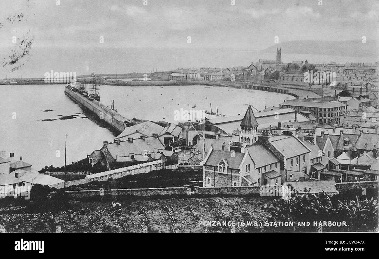 Eine Werbepostkarte der Great Western Railway zeigt einen Blick über den Hafen von Penzance. In der Bildmitte sind die Dächer des Bahnhofs zu sehen, rechts das gekrümmte Zughaus des Personenbahnhofs und das Gipfeldach des Güterschuppens auf der Elft bei der Hafenmauer. Stockfoto