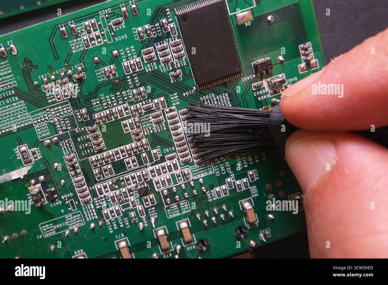 Wartung elektronischer Systeme. Reinigen des Staubs auf den oberflächlichen Halbleiterkomponenten digitaler Geräte. Stockfoto