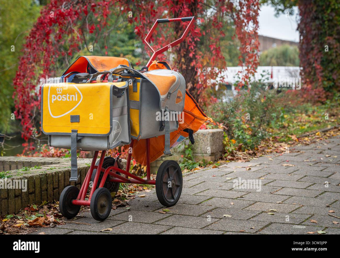 Amsterdam, Niederlande, 08.10.2025, PostNL Lieferwagen mit orangefarbenen Posttaschen auf dem Gehweg, niederländischer Post- und E-Commerce-Service Stockfoto