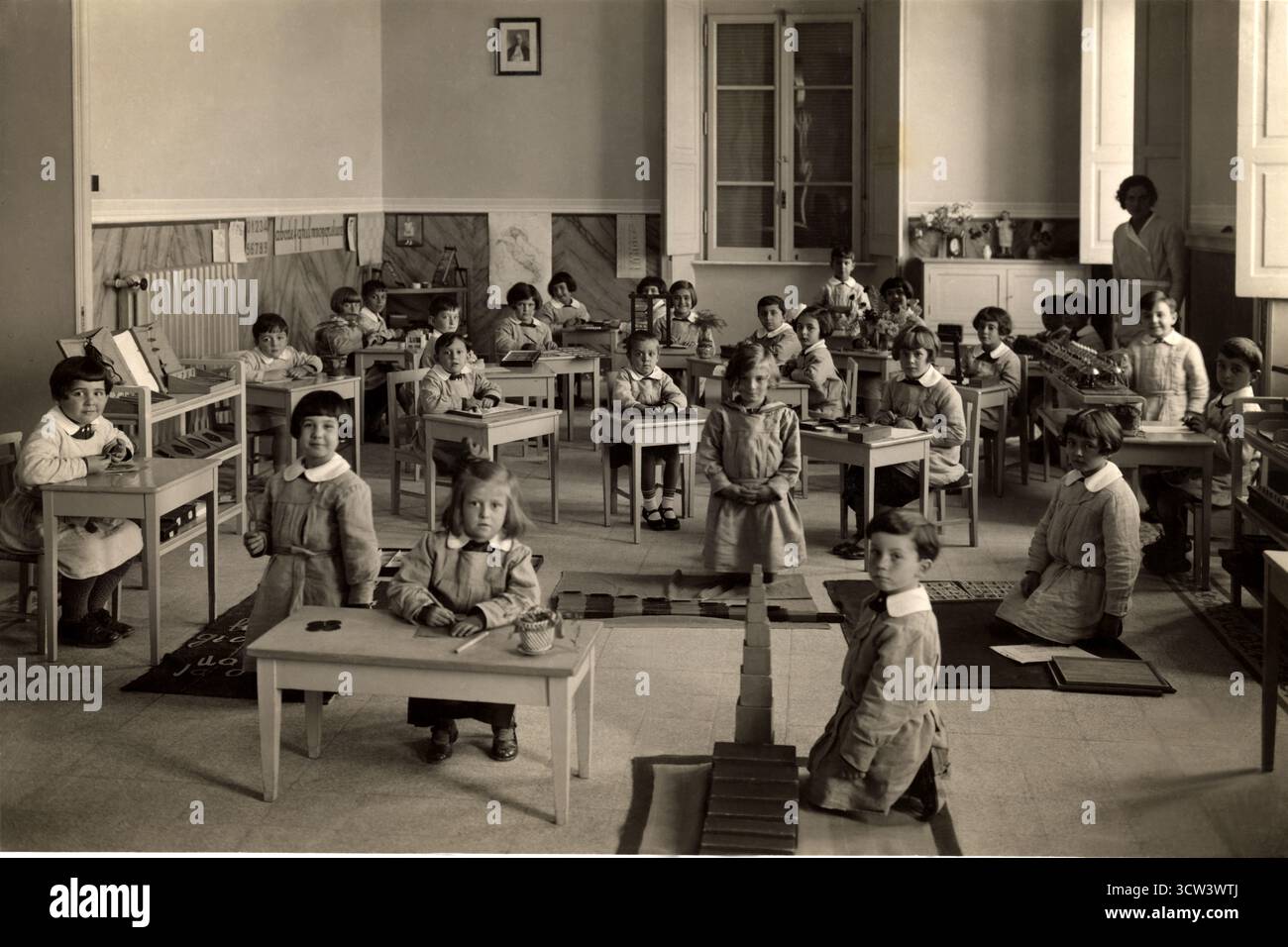 1935 v. Chr., GENUA , ITALIEN : eine italienische katholisch-liberale Montessori-Schule . MARIA MONTESSORI ( 1870–1952 ) war eine italienische Pädagogin und Pädagogin . Auf diesem Foto eine Schule der ERSTEN KLASSE ( PRIMA CLASSE ELEMENTARE SCOLASTICA con Metodo Educativo Montessoriano ) mit sechsjährigen Schülern. In Italien wurde die Montessori-Methode während des zwanzigjährigen faschistischen Regimes, das von Diktator Benito Mussolini auferlegt wurde, als zu libertär angesehen. Sie wurde jedoch in vielen katholischen Schulen übernommen, die diese moderne Bildungsmethode sofort aufgriffen. Mussolini war sofort gegen Montessor Stockfoto