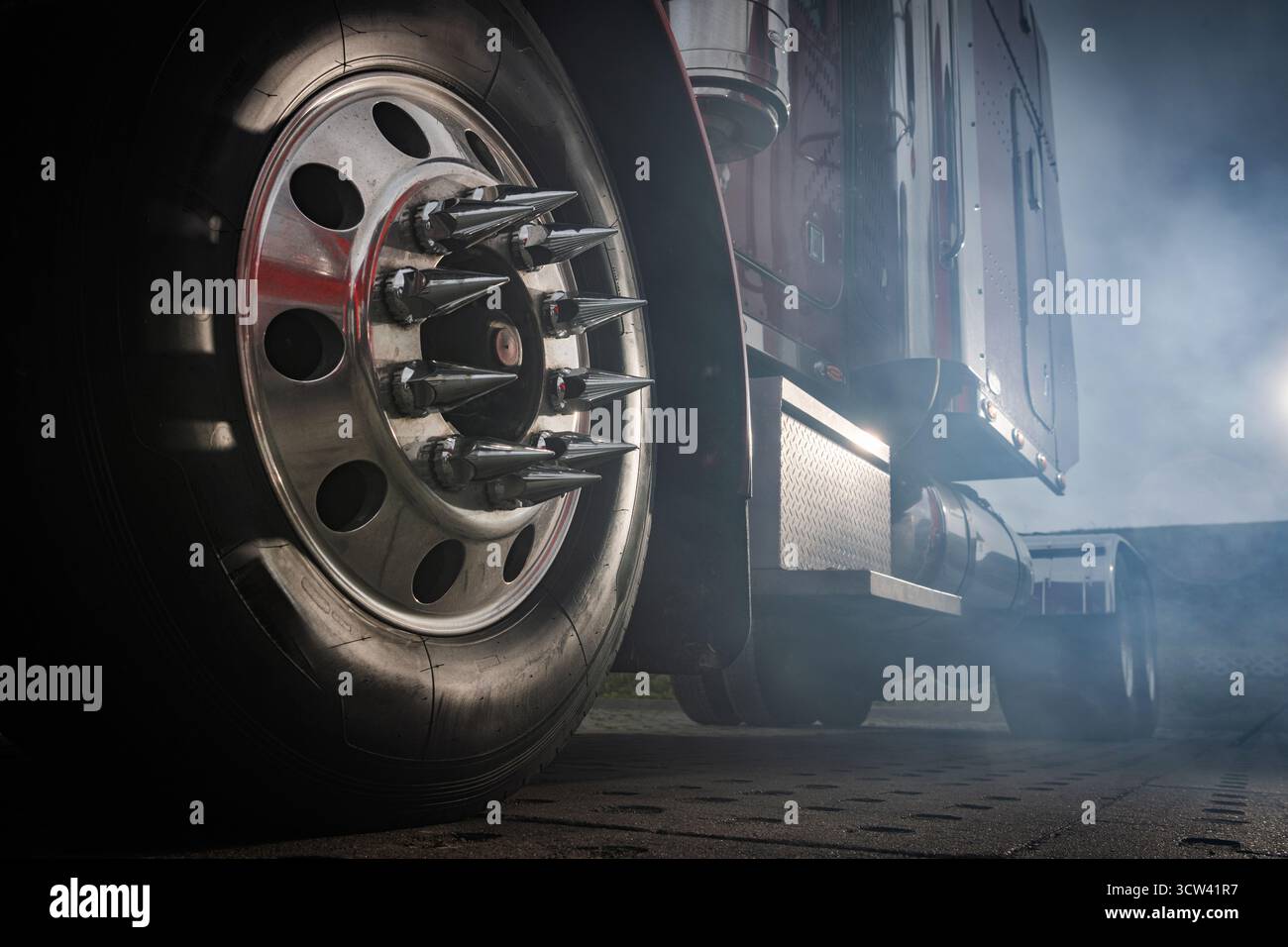 Ein robustes Lkw-Rad verfügt über scharfe Spitzen, die in der Dämmerung von rauchhaltigem Rauch umhüllt sind und eine beeindruckende und kraftvolle Präsenz auf der Straße zeigen. Stockfoto