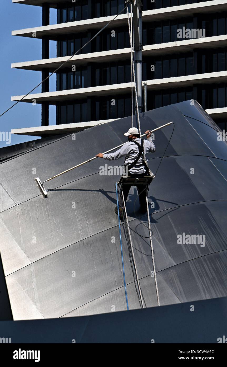 LOS ANGELES, KALIFORNIEN - 07. OCT 2025: Ein Wartungspersonal mit einem Sicherheitsgurt reinigt das Äußere der Disney Concert Hall. Stockfoto