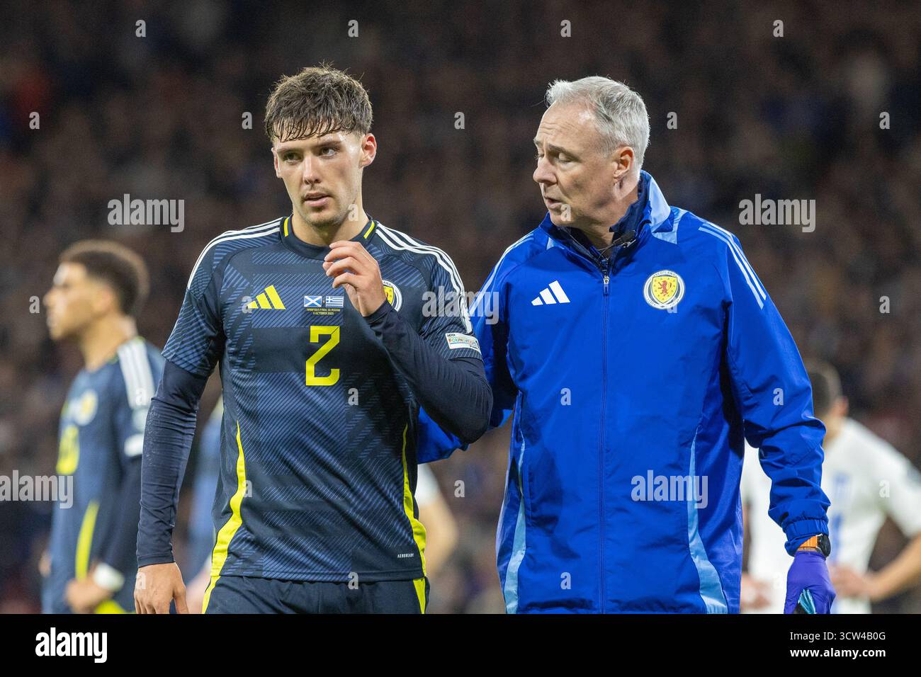 Glasgow, Großbritannien. Oktober 2025. Schottland spielte Griechenland in der WM-Europameisterschaft im Hampden Park, Glasgow, Schottland. Hampden Park ist das Heimstadion der schottischen Fußballnationalmannschaft. Das Finale war Schottland mit 3:1 Griechenland. Aaron Hickey (S2) wird innerhalb von 58 Minuten nach einer Beinverletzung vom Spielfeld begleitet Credit: Findlay/Alamy Live News Stockfoto