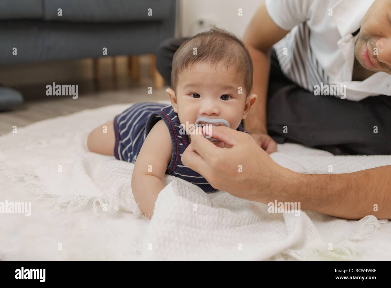 Ein Vater verbringt wertvolle Zeit mit seinem Baby, spielt und verbindet sich durch sanfte Pflege und lustige Momente auf einer weichen Matte. Das Baby erforscht die Bauchzeit und die Pa Stockfoto