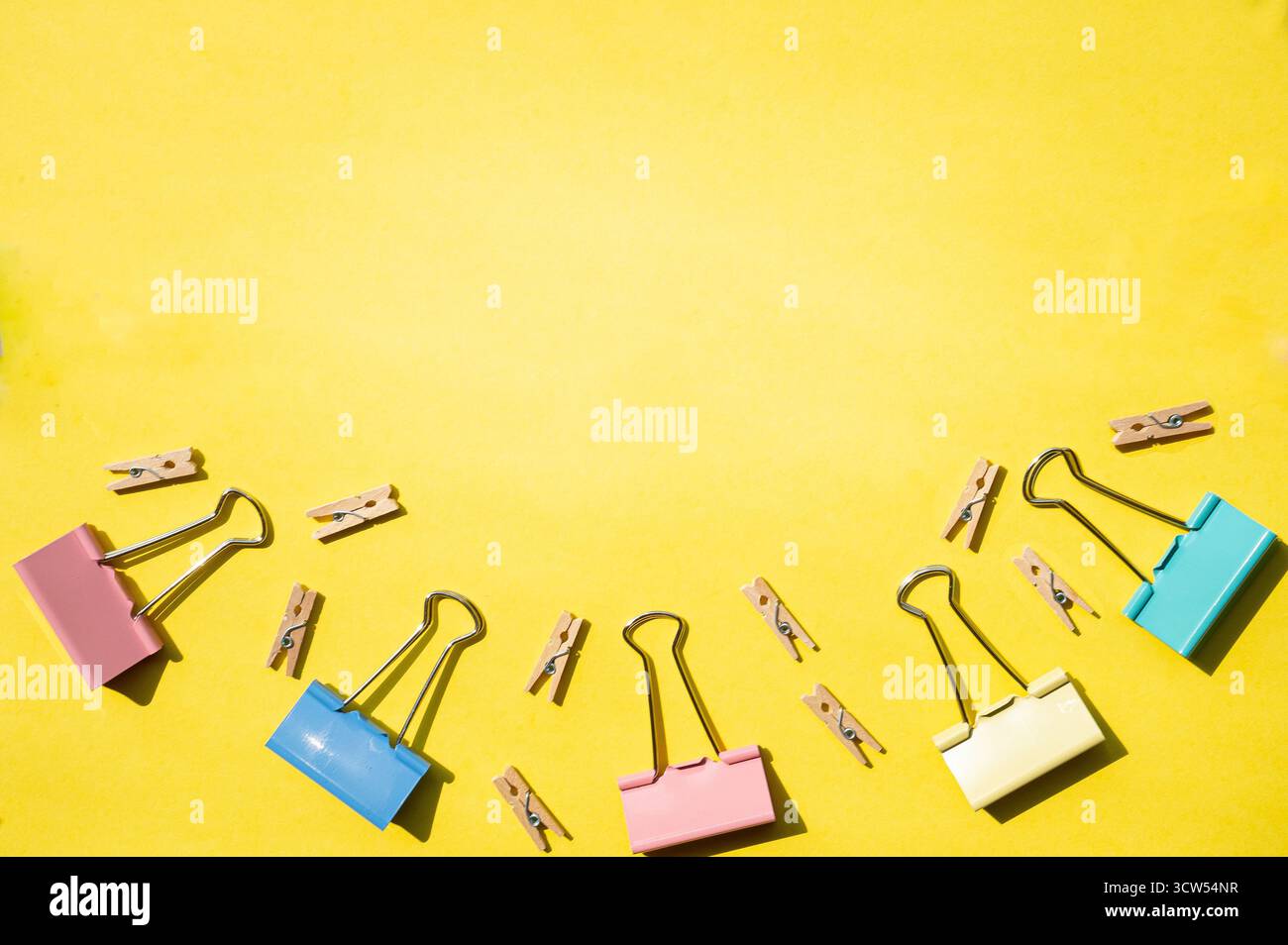 Büroklammern sind auf gelbem Schreibtisch angeordnet. Konzept von Organisation, Schule, Studium, Bürobedarf und Kreativität. Stockfoto