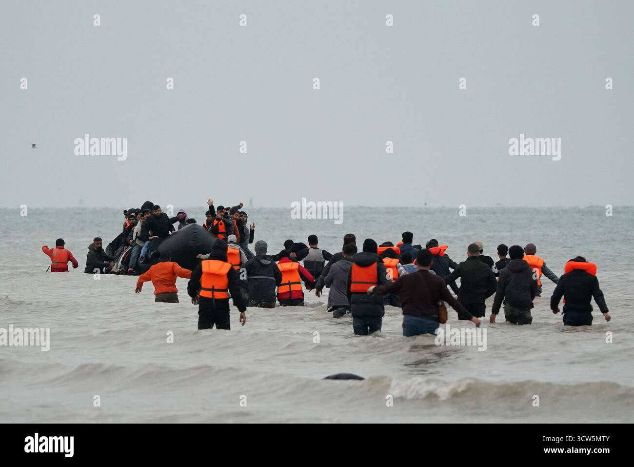 Menschen, die als Migranten gelten, waten ins Meer, um an Bord eines kleinen Bootes in Gravelines, Frankreich, zu gehen. Bilddatum: Freitag, 10. Oktober 2025. Stockfoto
