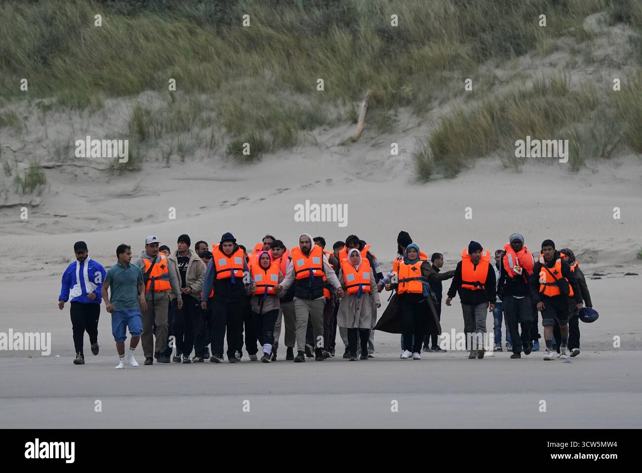 Menschen, die als Migranten gelten, warten am Strand in Gravelines, Frankreich, auf ein kleines Boot. Bilddatum: Freitag, 10. Oktober 2025. Stockfoto