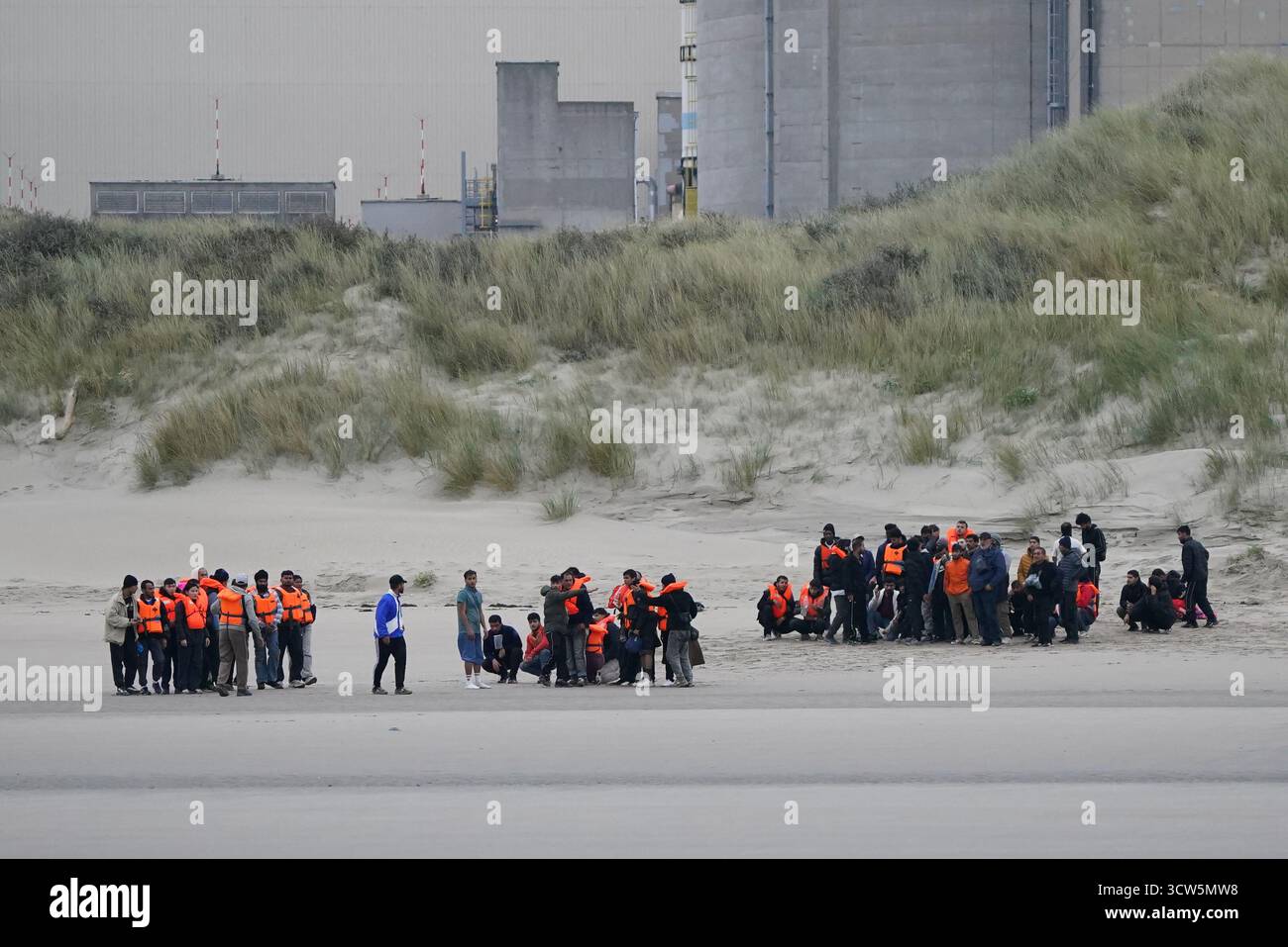 Menschen, die als Migranten gelten, warten am Strand in Gravelines, Frankreich, auf ein kleines Boot. Bilddatum: Freitag, 10. Oktober 2025. Stockfoto