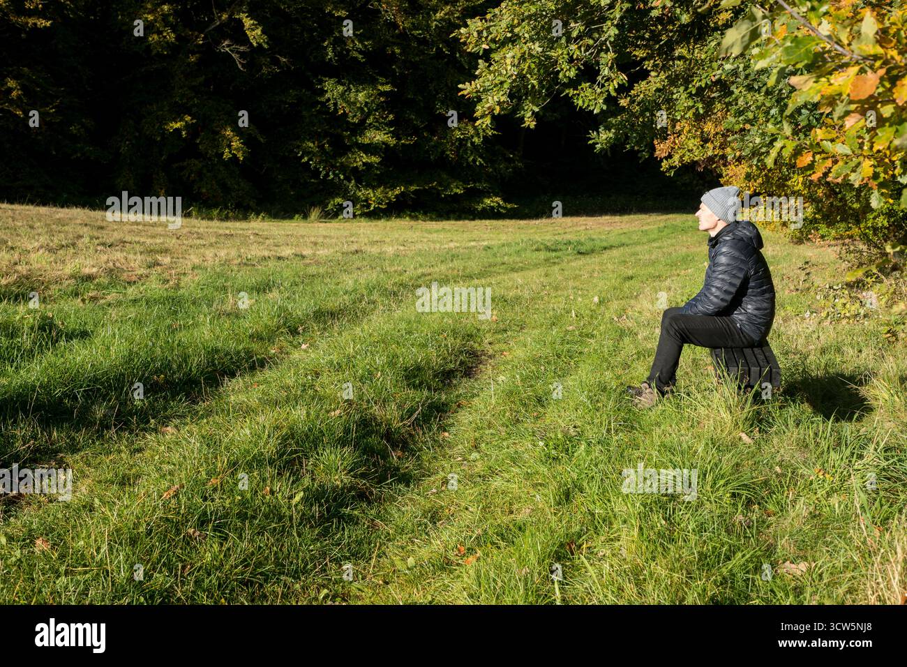 Mann, der auf der Bank sitzt, genießt die Herbstsonne auf seinem Gesicht in ruhigem Moment allein, friedlichem Moment Stockfoto