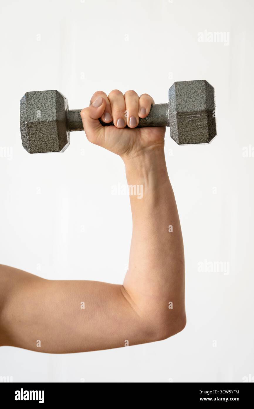 Nahaufnahme eines Arms, der eine graue Kurzhantel hob Stockfoto