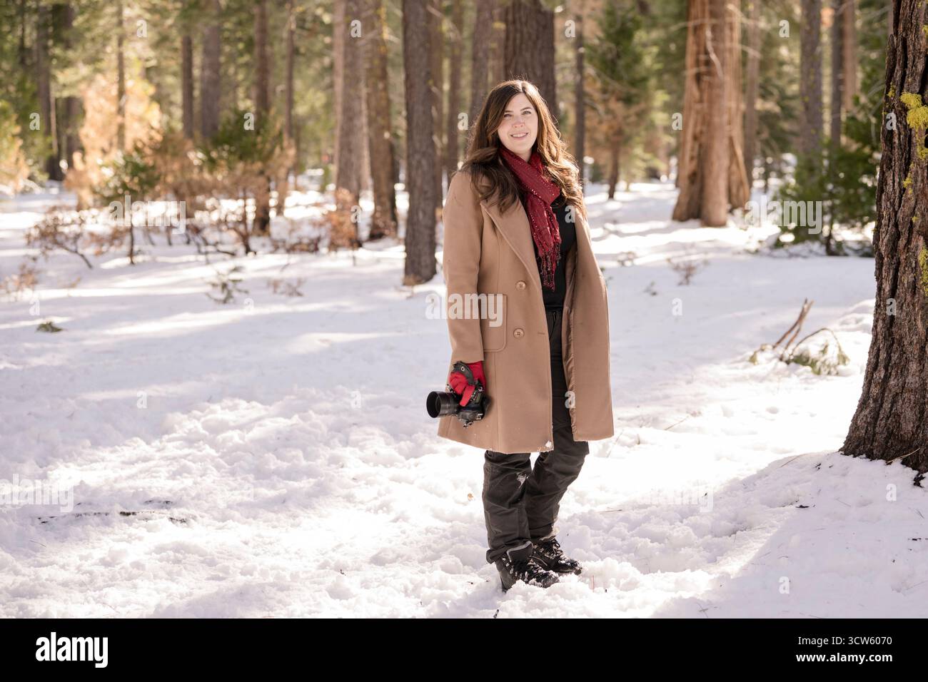 Frau, die im Schnee läuft und eine Kamera hält Stockfoto