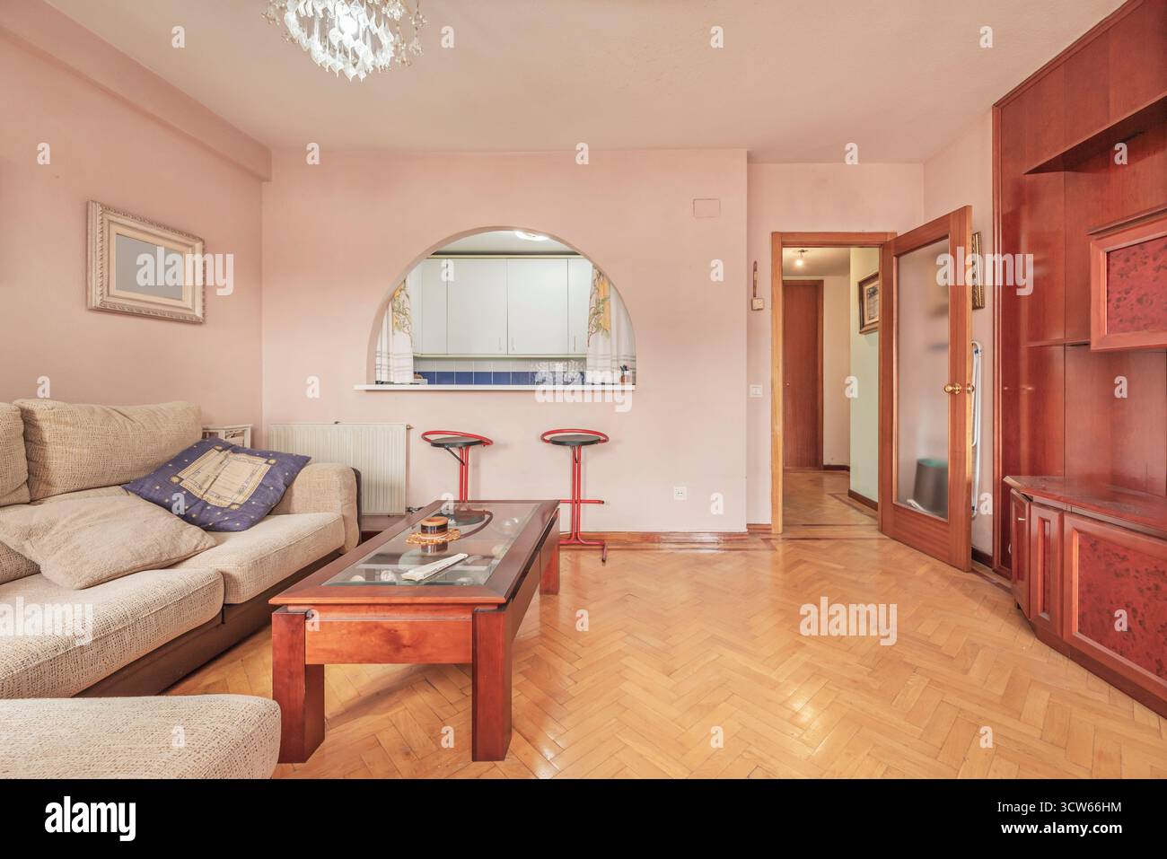 Wohn- und Essbereich mit grauem Leinensofa, Lesesessel, hölzerner Esstisch und offenen Regalen Stockfoto