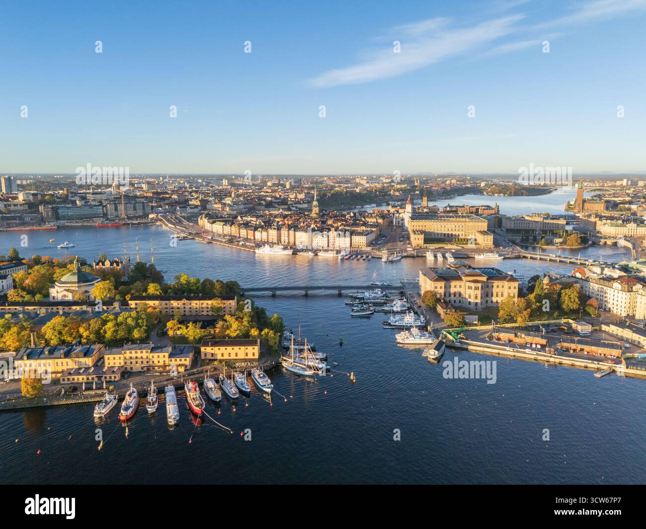 Aus der Vogelperspektive auf die pulsierende Stadt mit Booten im Vordergrund und die Stadtlandschaft mit Stadshuset, Stockholm, Stockholmer County, Schweden. Stockfoto