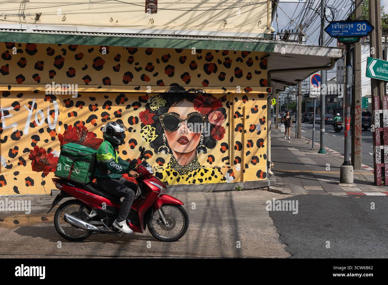 Bangkok, Thailand. Oktober 2025. Ein Motorrad passiert ein Wandgemälde, das ursprünglich von der spanischen Straßenkünstlerin Carolina Adán Caro entworfen wurde und von thailändischen Künstlern vollständig restauriert wurde, nachdem sie auf der Charoen Krung Soi 30 zerstört wurde. Das Kunstwerk ist Teil des Projekts „Krung Thep Creative Streets“, das 15 internationale Künstler zusammenbrachte, um Wandbilder an 15 Standorten zu kreieren. Quelle: SOPA Images Limited/Alamy Live News Stockfoto