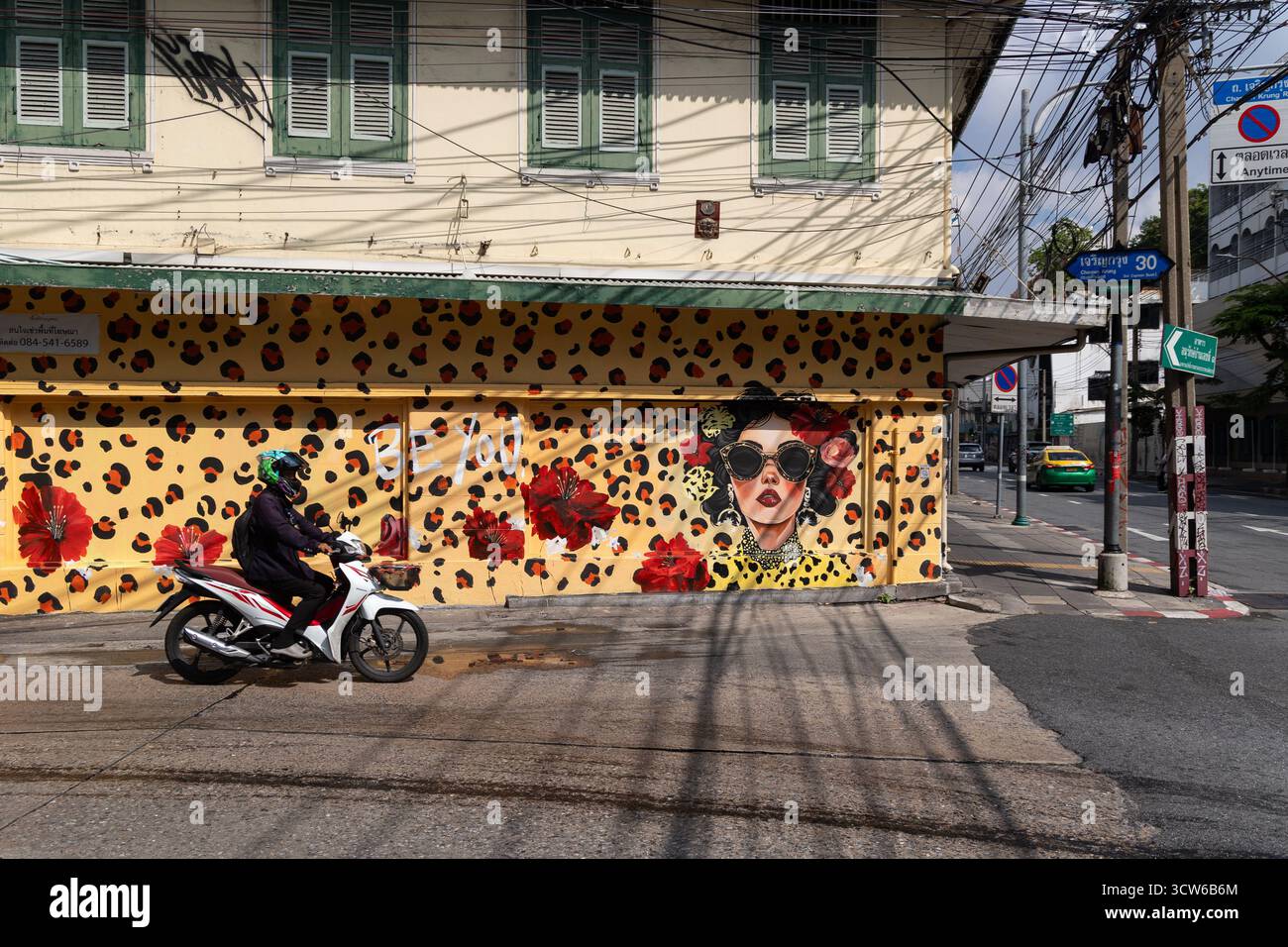 Bangkok, Thailand. Oktober 2025. Ein Motorrad passiert ein Wandgemälde, das ursprünglich von der spanischen Straßenkünstlerin Carolina Adán Caro entworfen wurde und von thailändischen Künstlern vollständig restauriert wurde, nachdem sie auf der Charoen Krung Soi 30 zerstört wurde. Das Kunstwerk ist Teil des Projekts „Krung Thep Creative Streets“, das 15 internationale Künstler zusammenbrachte, um Wandbilder an 15 Standorten zu kreieren. Quelle: SOPA Images Limited/Alamy Live News Stockfoto