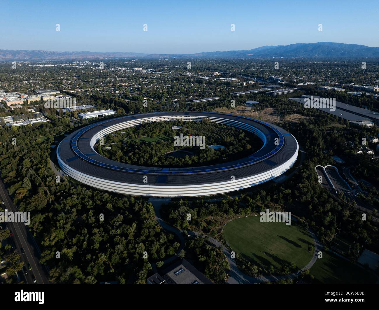Cupertino, USA - 5. September 2025: Aus der Vogelperspektive auf das legendäre Hauptquartier des Apple Parks, ein futuristischer Ring inmitten eines Meeres aus smaragdgrünen Bäumen, getaucht in das warme Licht der kalifornischen Sonne. Stockfoto