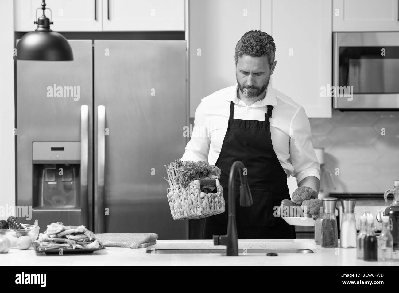 Koch Koch Mann, der Essen zubereitet. Man kocht in der modernen Küche. Kochen gesunder Salat. Koch kocht auf Schürze. Mann kocht in der Küche. Vorbereitung Stockfoto